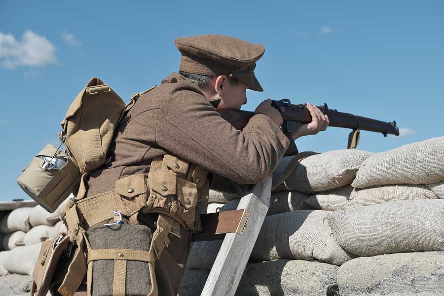 Re-enactor wearing WW1 uniform with replica gun in Shoreham Fort memorial trench West Sussex