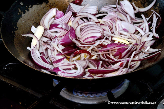 Frying red onion in a wok