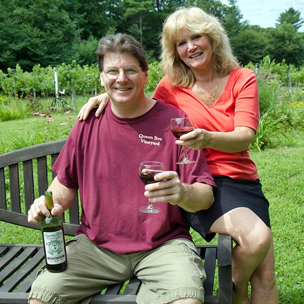 Nancy and Roy McGuill sitting on a bench, each holding a glass of wine