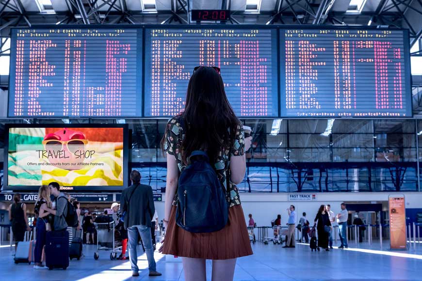 Person looking at airport departure and arrival boards - Flight deals