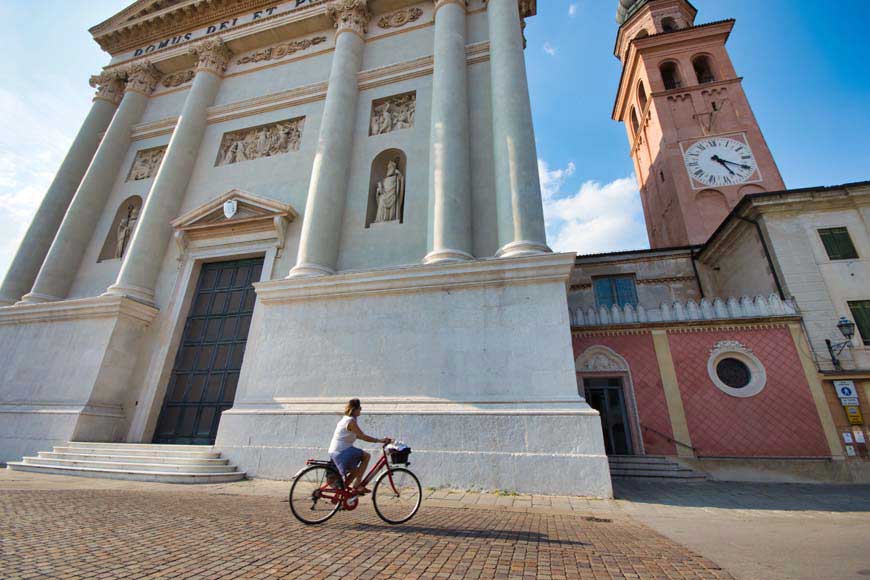 Person riding a bicycle past Cittadella Duomo, Veneto Italy
