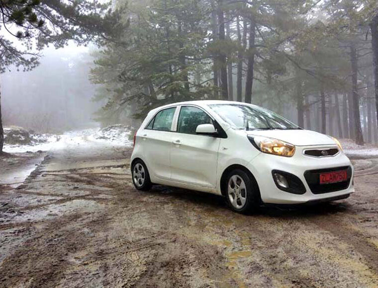 Holiday rental car parked on a snowy, muddy track in the Troodos Mountains, Cyprus