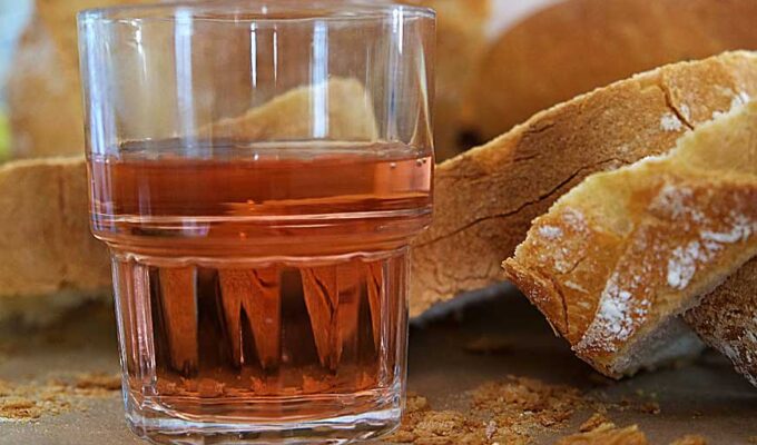 A glass of Rosé wine and slices of baguette