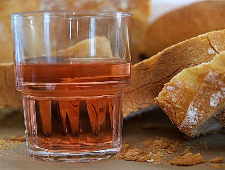 A glass of Rosé wine and slices of baguette
