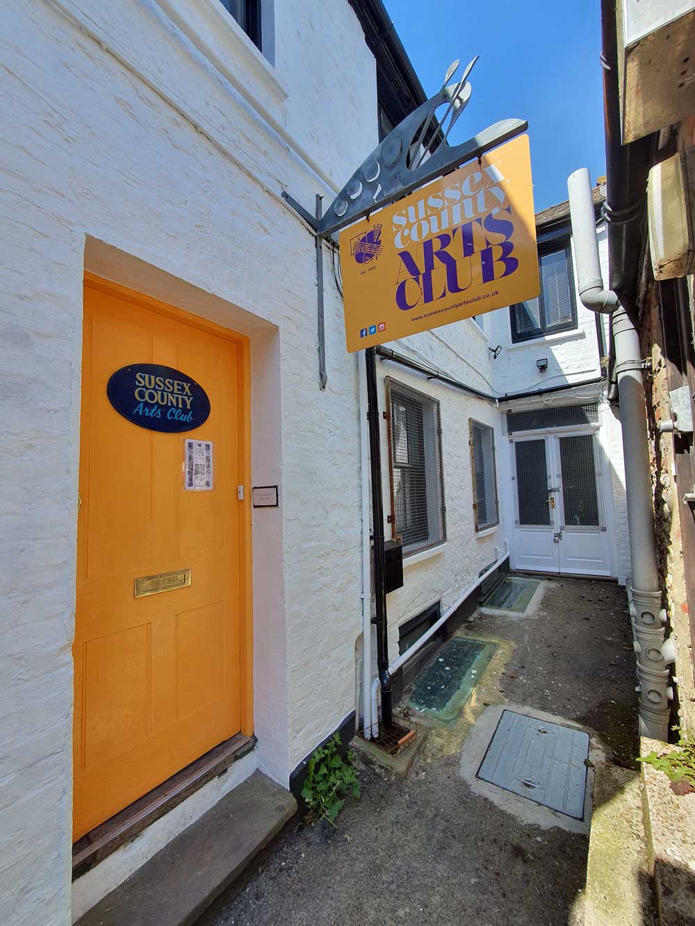 The yellow door of The Sussex County Arts Club Bond Street Cottages Brighton