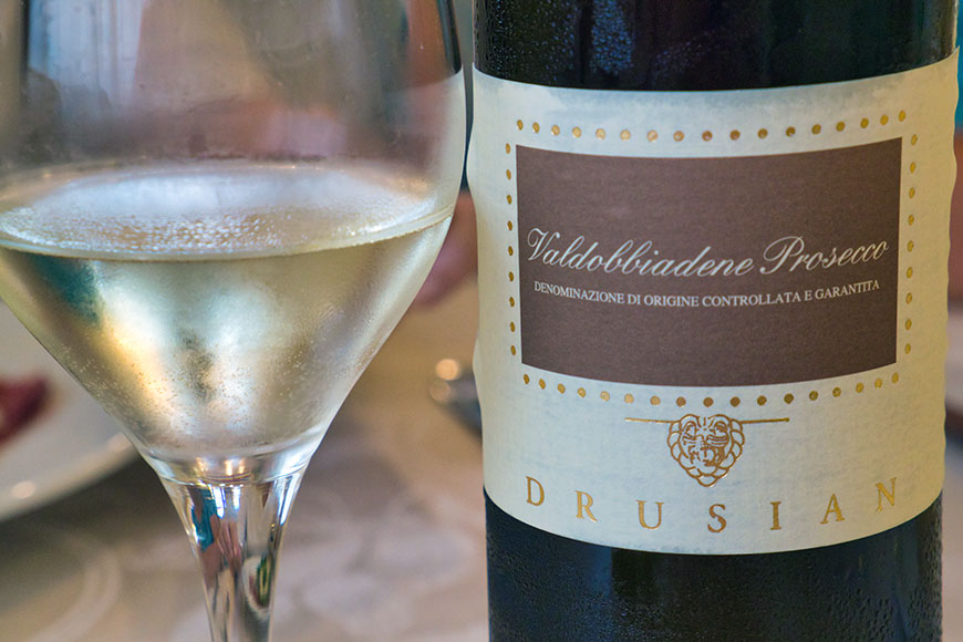 A close-up of the bottle label and glass of Valdobbiadene Still Prosecco