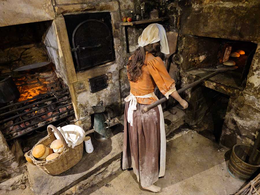 Mannequin of Sally Lunn working in her kitchen making buns at the Sally Lunn Museum in Bath, UK