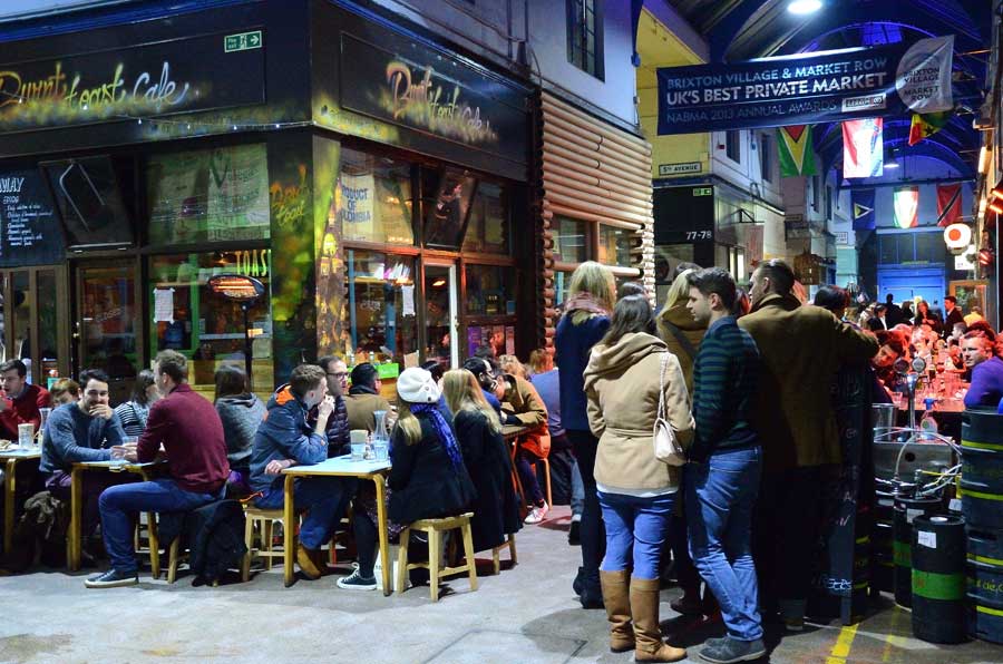 People in the restaurants and bars in Brixton Market arcade