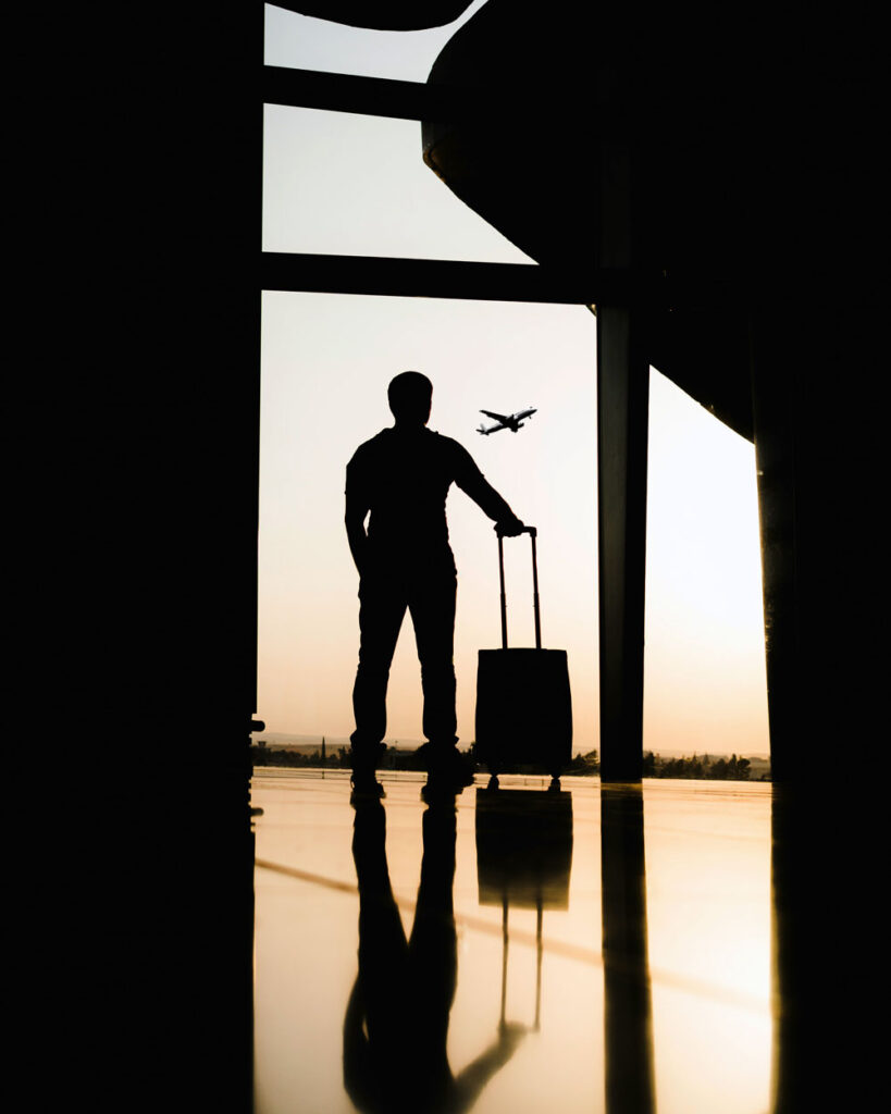 Silhouette of man at airport watching aircraft take off ©Yousef Alfuhigi Unsplash