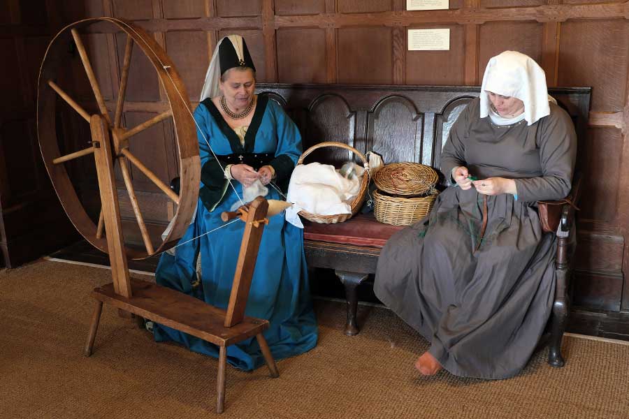 Tudor re-enactors in costume, demonstrating spinning and braiding at Michelham Priory in Upper Dicker, East Sussex, England, United Kingdom