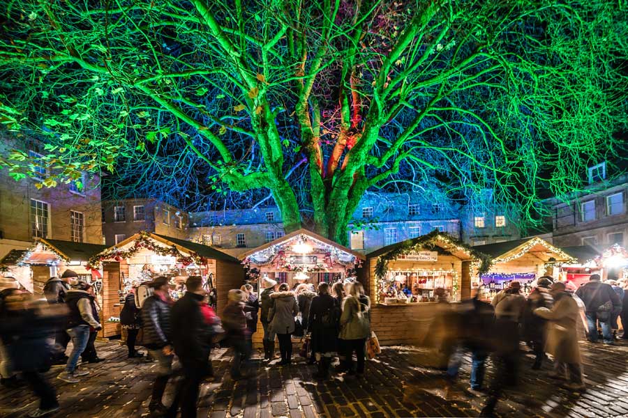Christmas market stalls under the trees in Abbey Green Bath UK
