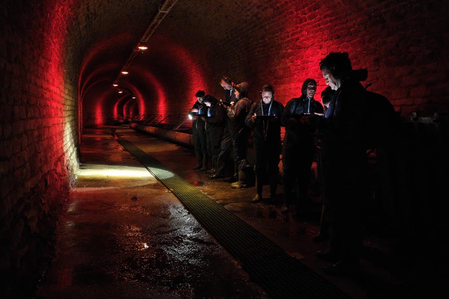 Guided tour checking their iPads in historic former canals and sewers under Antwerp Belgium