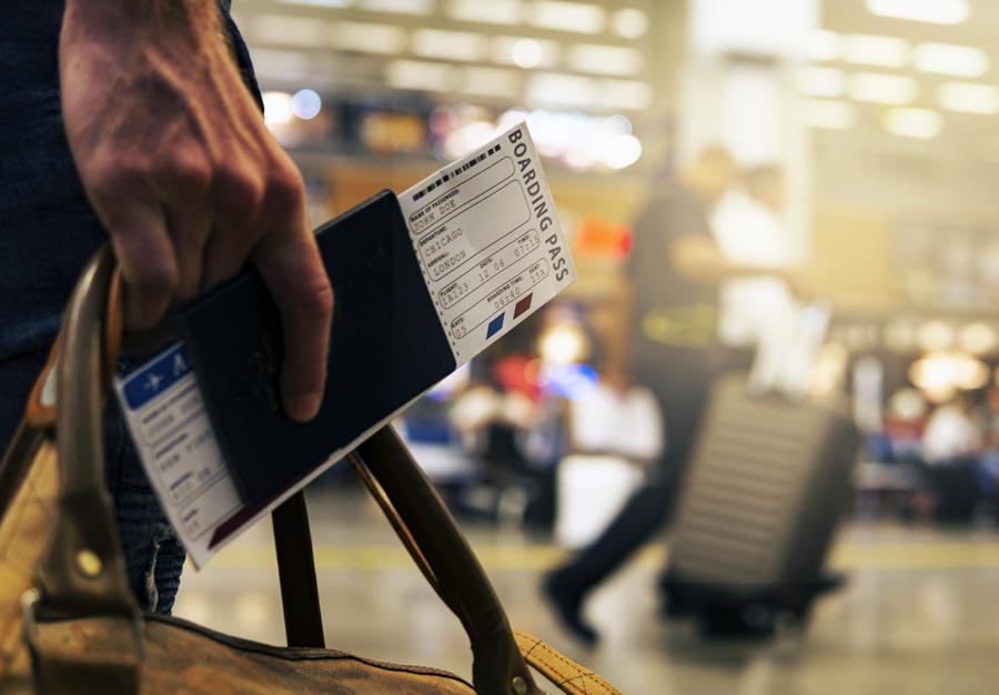 Close up of person with passport boarding pass and bag in airport departure lounge
