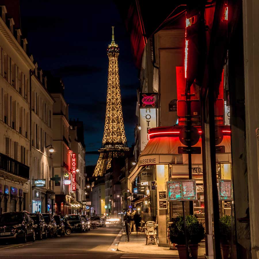 Illuminated Eiffel Tower and Paris street lit with neon shop and restaurant lights
Image by Edouard Grillot / Unsplash