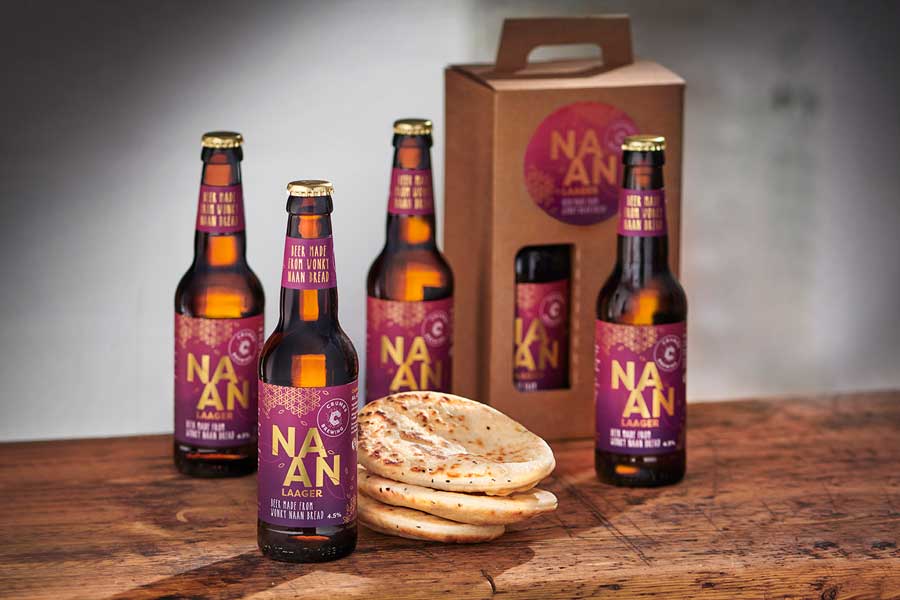 Bottles of Naan Laager from Crumbs Brewing and naan breads on a wooden table