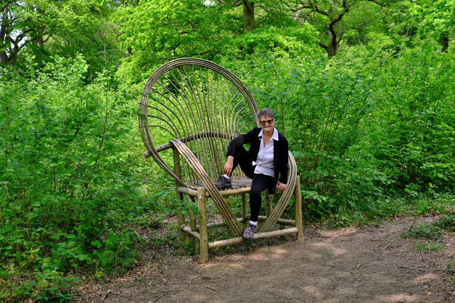 Person sitting on oversize wicker chair on the Pearcelands Wood Sculpture Trail Wakehurst
