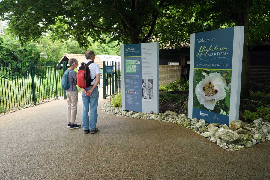 Two people looking at notice boards at the entrance to Highdown Gardens Worthing West Sussex UK