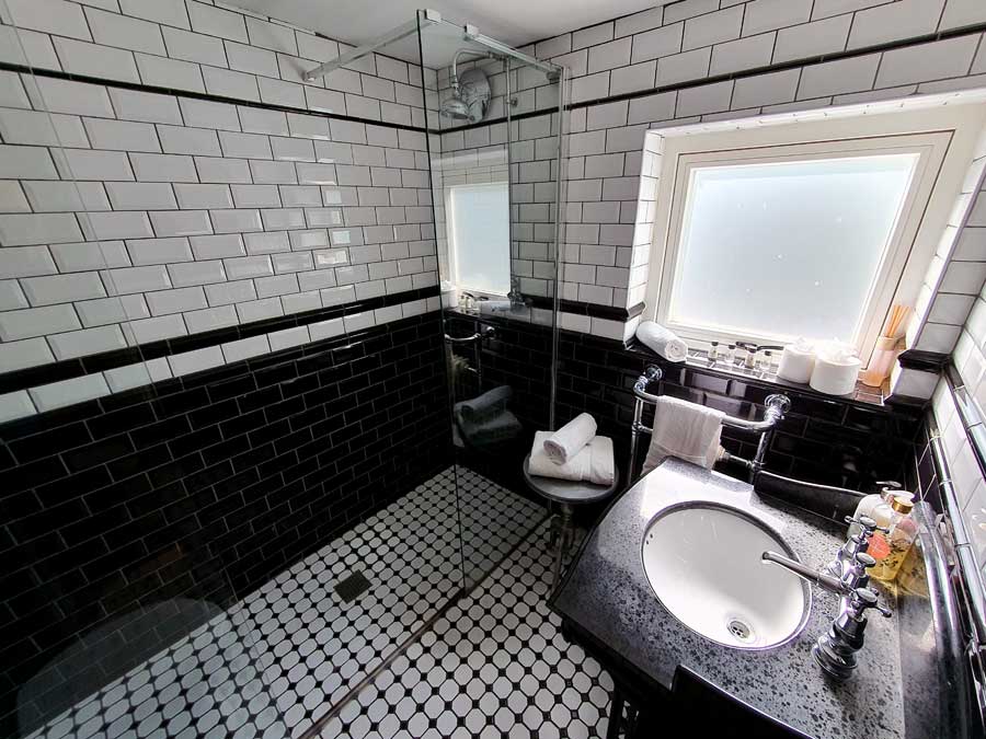Shower room with black and white tiles at Looking Glass Cottage, Brighton, UK