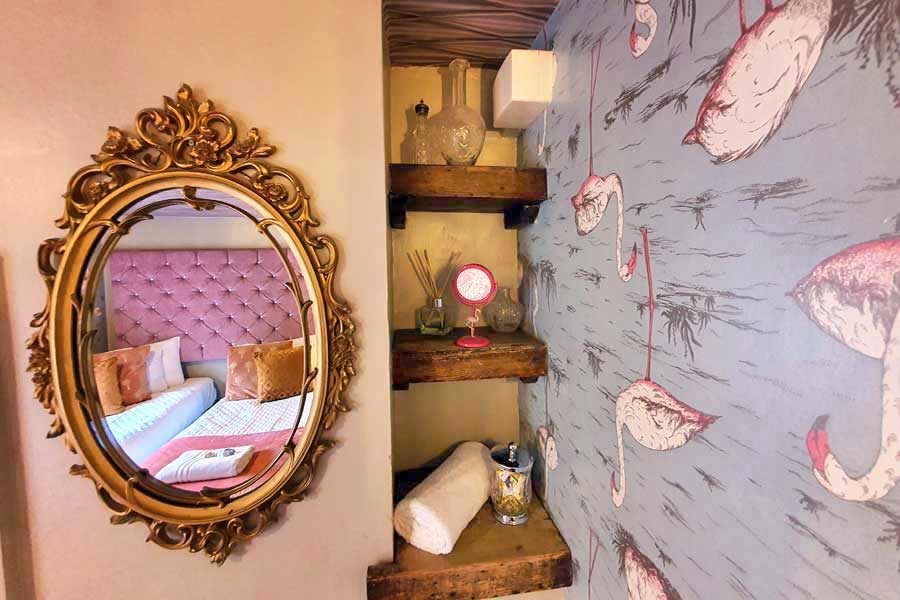 Upside-down flamingo wallpaper and mirror reflecting the beds at Looking Glass Cottage, Brighton, UK