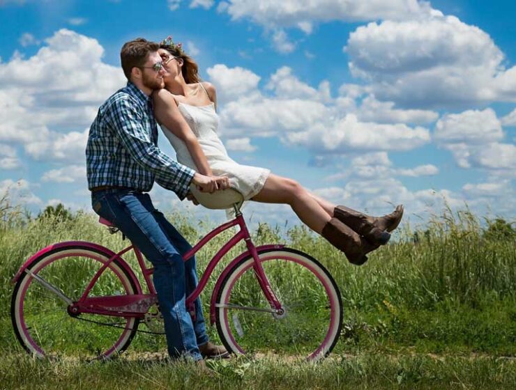 Male riding bicycle with female on handlebars in countryside
