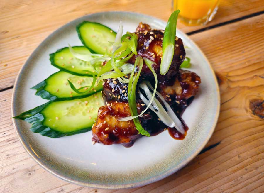 Cauliflower in sticky sauce, served on a plate with slices of cucumber and spring onion