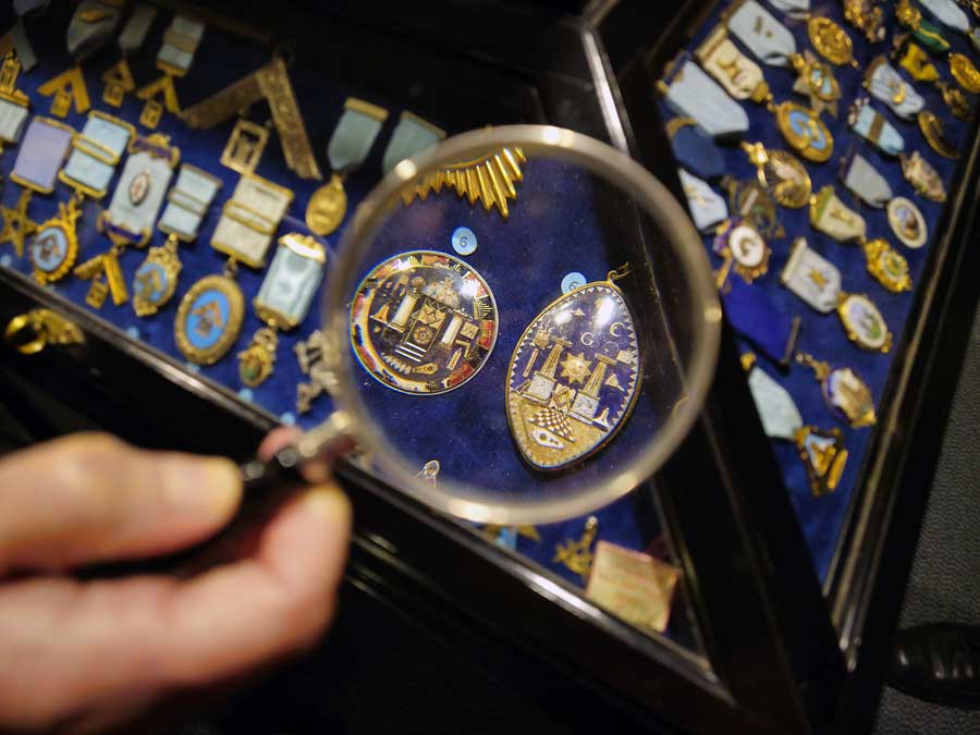 Magnifying glass showing details of breast jewels in display cabinet at Masonic Museum, Bath, UK