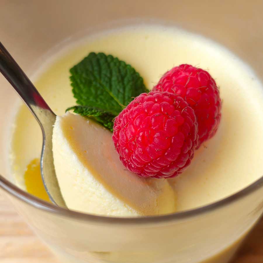Lemon posset with raspberries and mint garnish