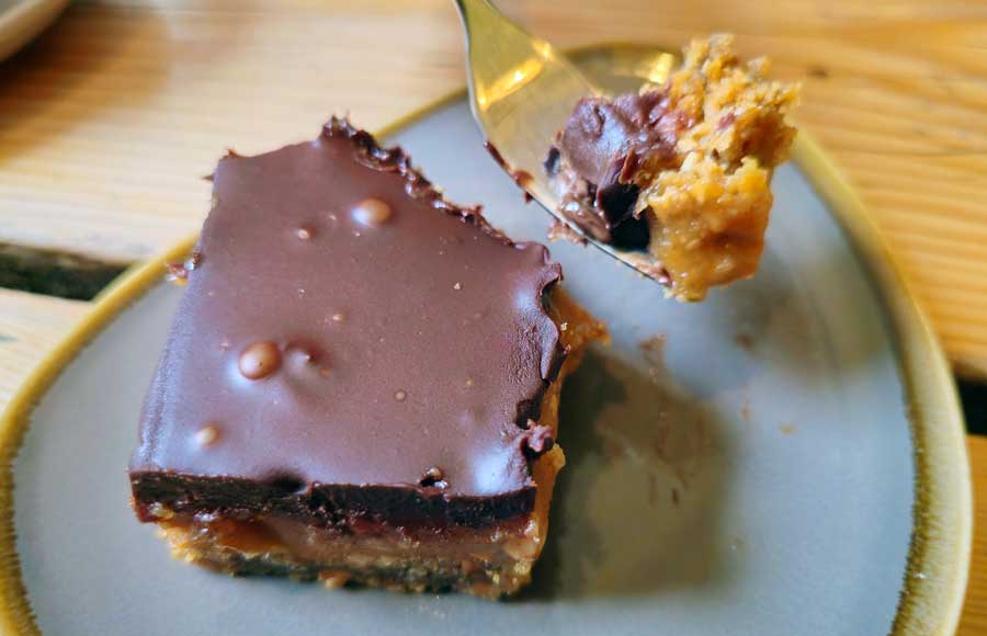Slice of Peanut butter square traybake topped with chocolate