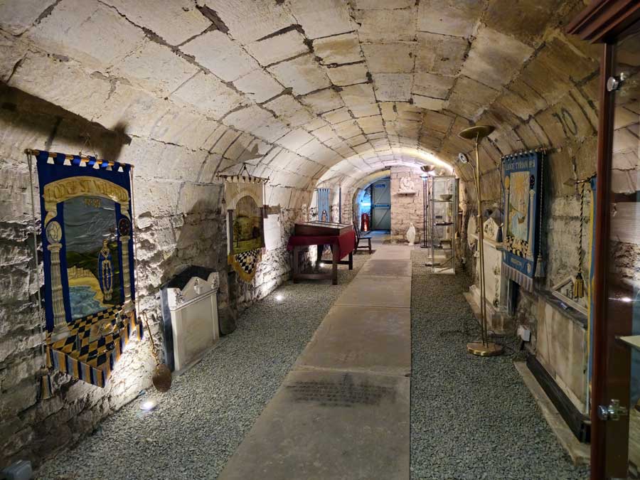 Vaults in the Masonic Hall Bath UK, once used for Catholic burials, now part of the Masonic Museum, showing pennants, statues and old gravestones