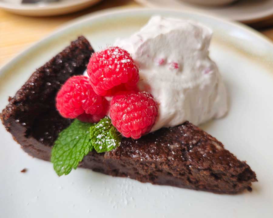Vegan Swedish chocolate mud cake served with raspberry cream and raspberries