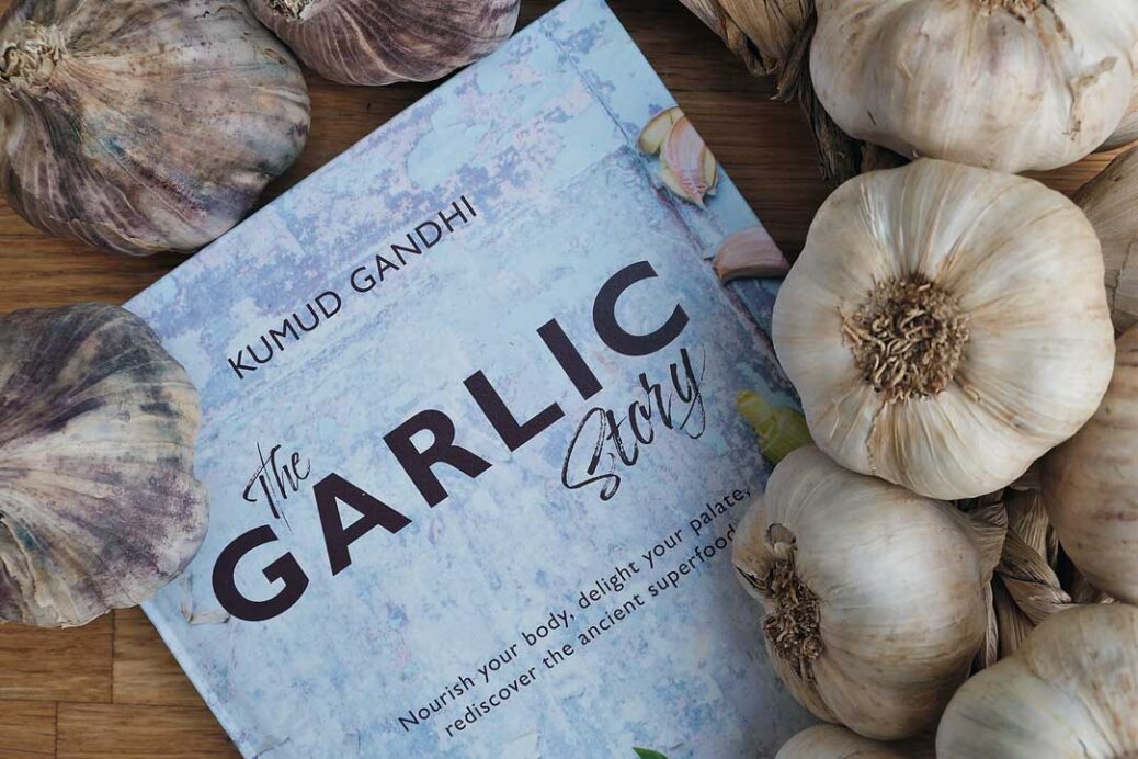 Garlic bulbs surrounding the book The Garlic Story by Kumud Gandhi