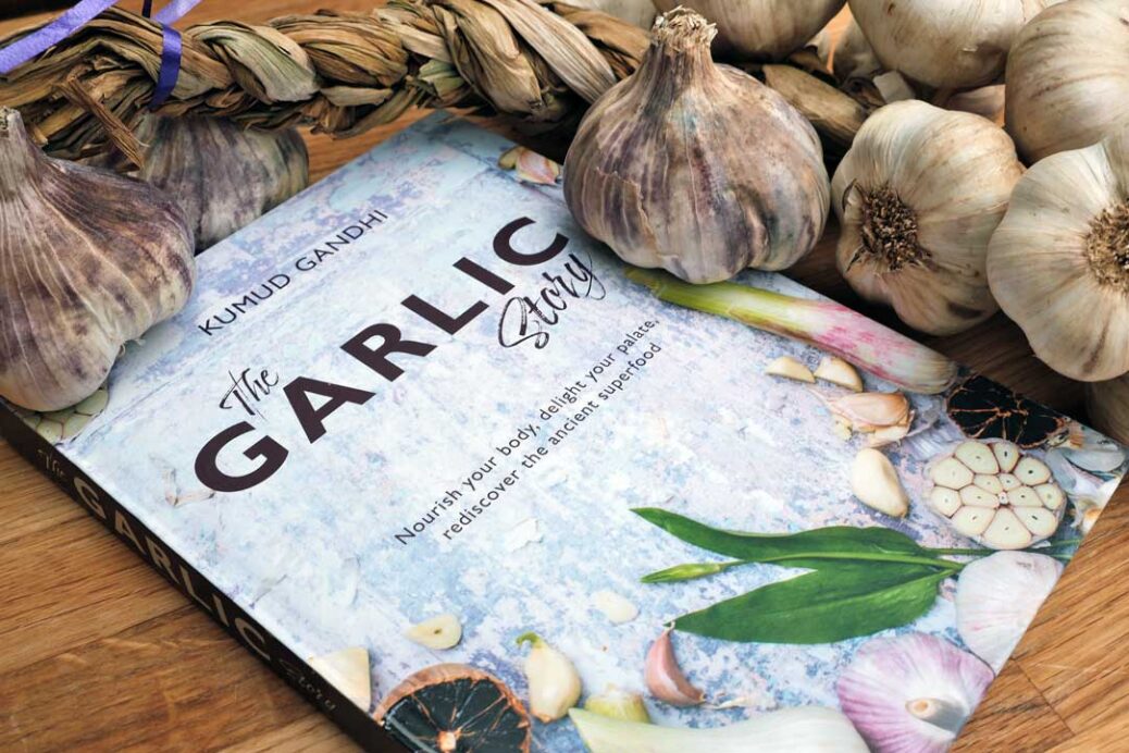The Garlic story recipe book by Kumud Gandhi surrounded by garlic bulbs