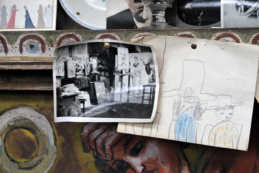 Old black and white photograph of the art studio at Charleston Farmhouse pinned to the decorated fireplace