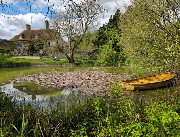Pond with wooden rowing boat in the garden of Charleston Farmhouse Firle East Sussex