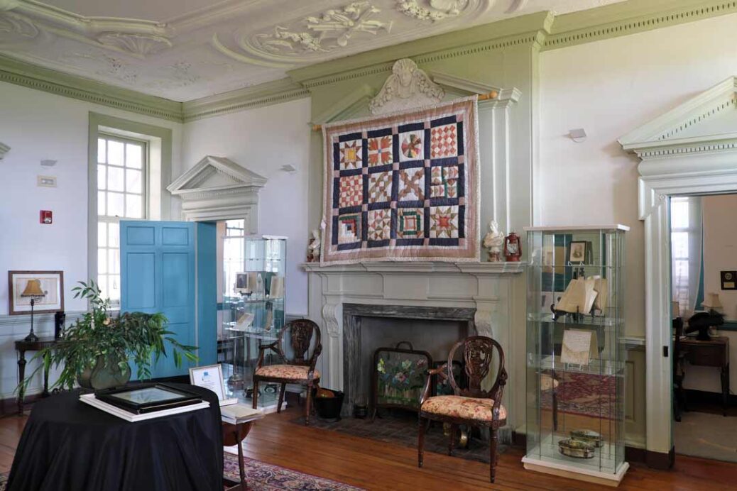Reception room at the Belmont Mansion Philadelphia showing reproduction quilt, fireplace and furniture