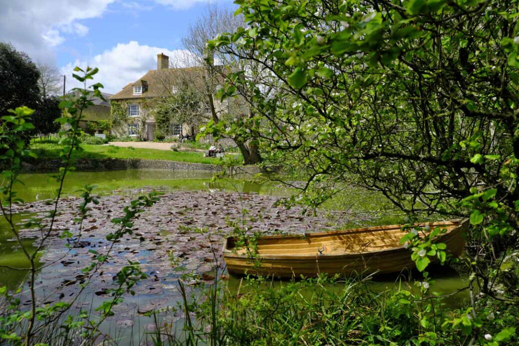 Charleston Farmhouse with wooden rowing boat and pond in foreground Firle East Sussex