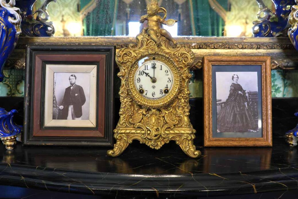 Black and white photographs of Ebenezer and Anna Maxwell either side of a gold clock on mantlepiece in parlour at Ebenezer Maxwell Mansion Philadelphia