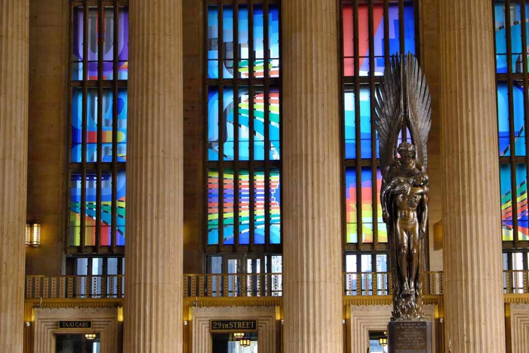 Coloured window art installation called Euphonic and Chromatic Drift by Adam Crawford, columns and World War 2 memorial statue at 30th street station Philadelphia Pennsylvania USA