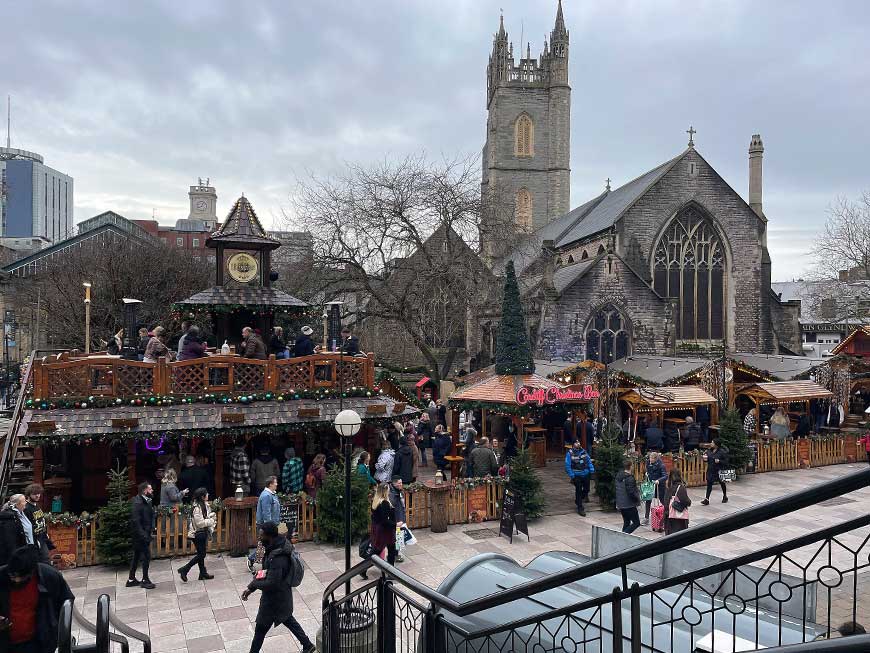Looking from some steps towards wooden stall and church in Working Street, Cardiff Christmas Market 2024