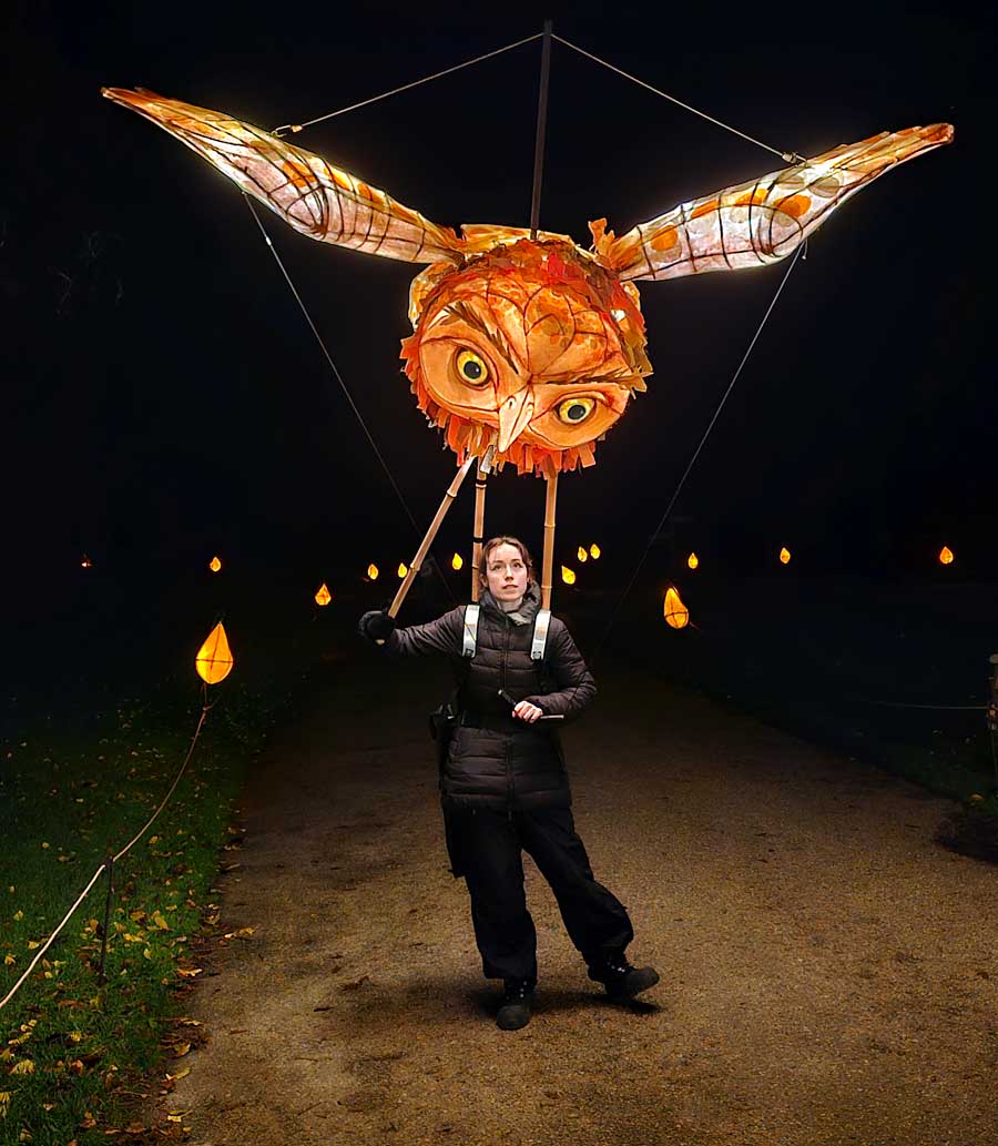 Puppeteer operating a giant illuminated owl lantern