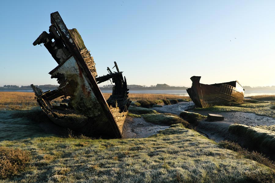 Early morning sunshine on wrecks of two fishing trawlers in the Wyre Estuary viewed from the Fleetwood Marsh Nature Reserve