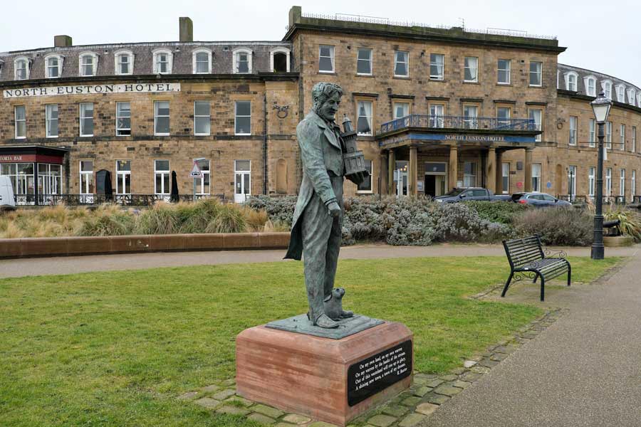 Statue of Sir Peter Hesketh Fleetwood with his model Lower Lighthouse and a rabbit at his feet in Euston Gardens. The North Euston Hotel is behind him