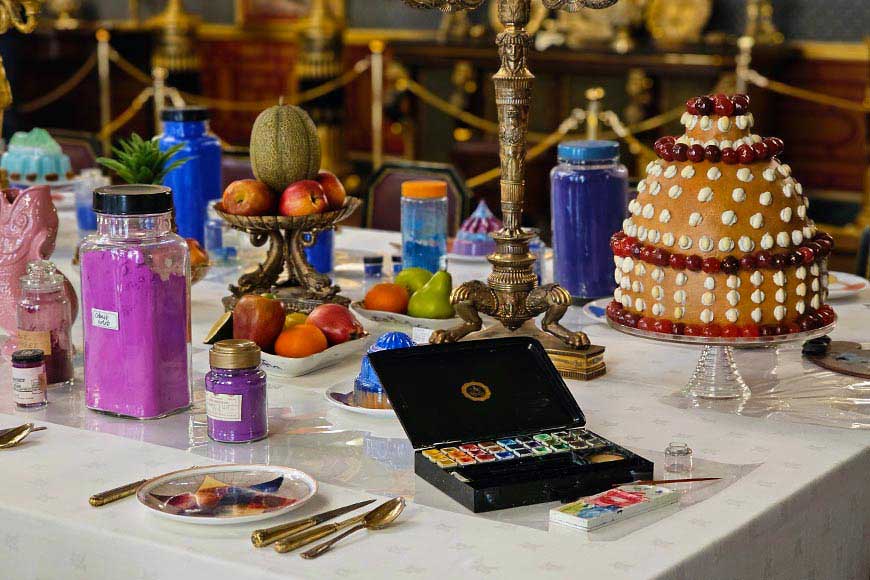 Jars of coloured pigment, paint box, and replica food on table for Colours exhibition at Royal Pavilion Brighton