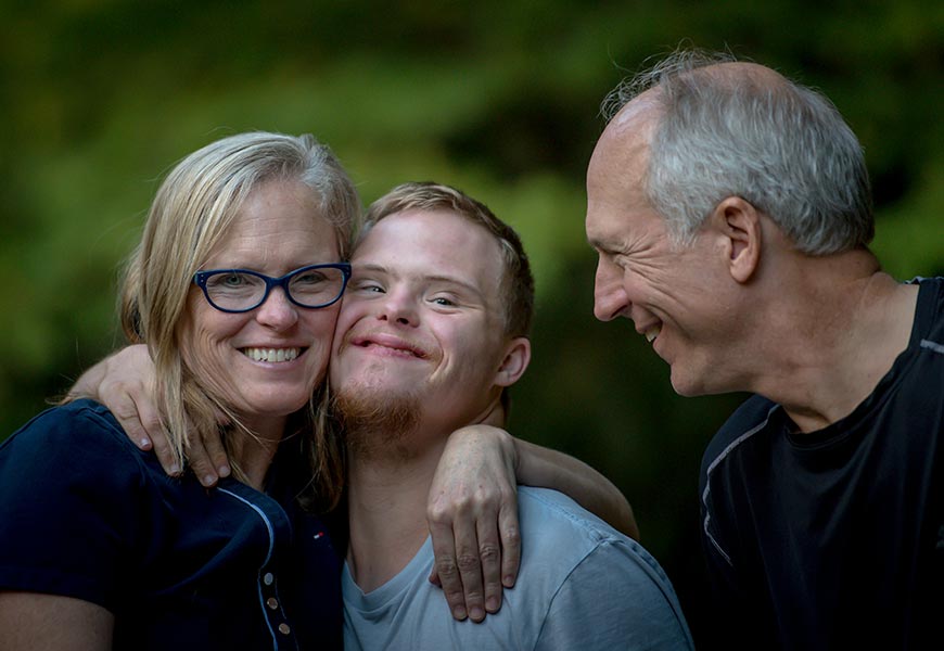Two men and one woman standing near a tree