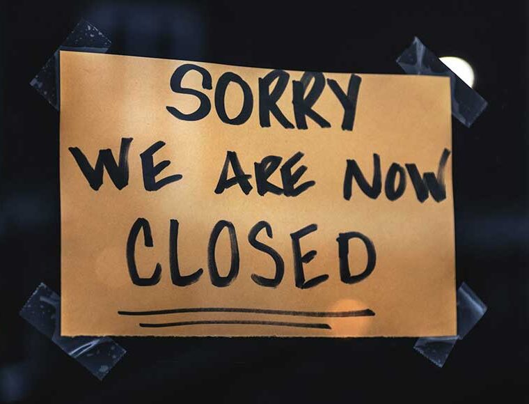 Sorry we are now closed, sign on brown card stuck with sticky tape in shop window