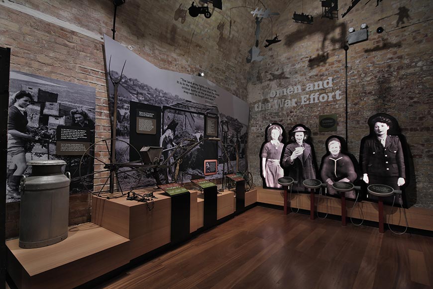 Women and the War Effort exhibition showing wartime farm tools and women in uniform at Newhaven Fort, East Sussex