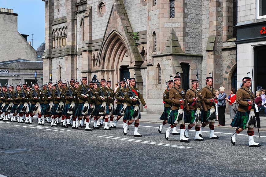 Soldiers in traditional Scottish attire, including kilts and sporrans marching through Aberdeen in Scotland
