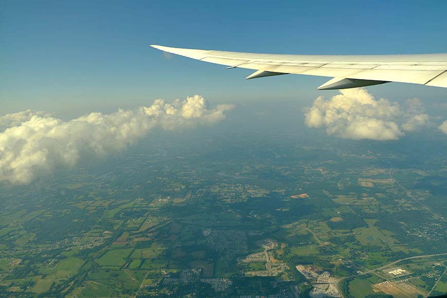 Aerial view from aircraft window of land and clouds