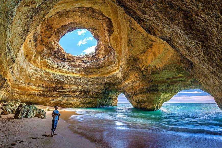 Male standing in the interior of the Benagil Cave, a famous sea cave located near Benagil Beach in the Algarve region of Portugal