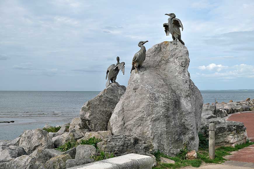 Steel cormorants on a large rock at the entrance to the Stone Jetty in Morecambe